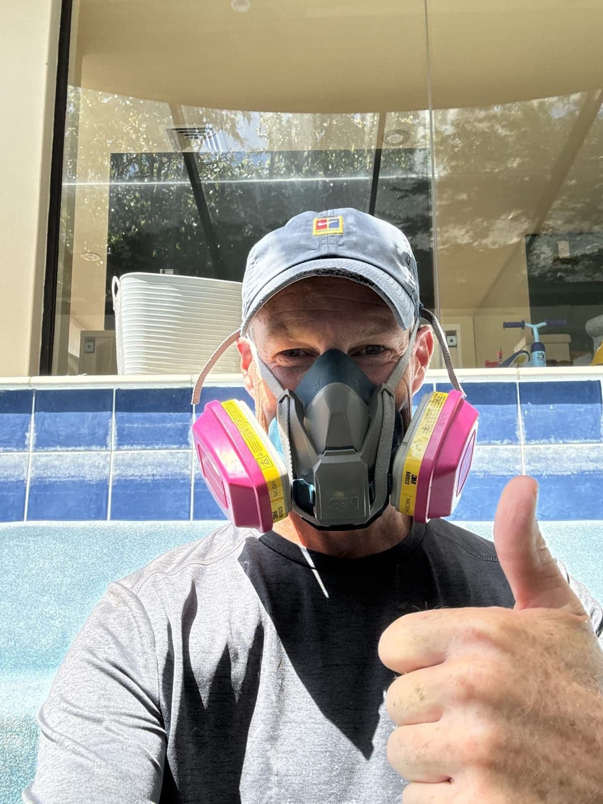 Andy in a respirator standing in a drained pool, set up for an acid wash